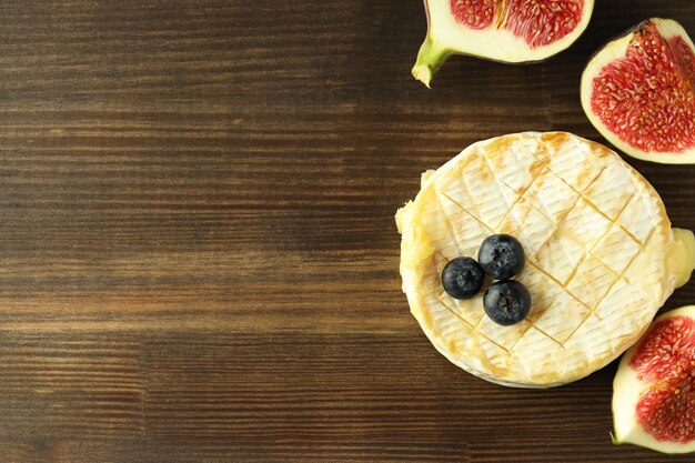 Concept of tasty food with grilled camembert on wooden background.
