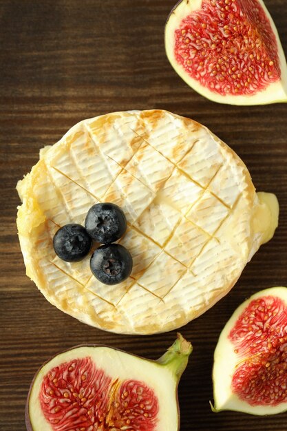 Concept of tasty food with grilled camembert on wooden background.