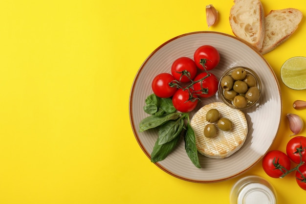 Concept of tasty food with grilled camembert on yellow background.