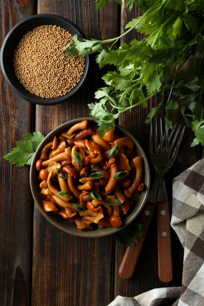 Photo concept of tasty food with marinated mushrooms on wooden table