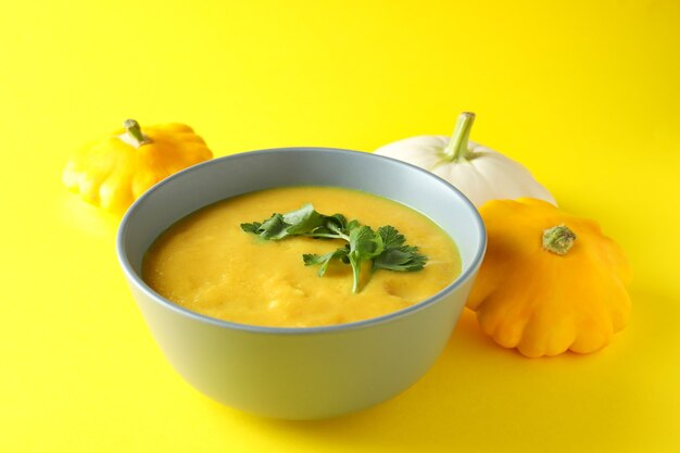 Concept of tasty food with pumpkin soup on yellow background