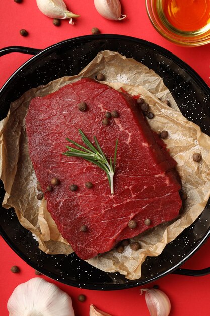 Photo concept of tasty food with raw beef steak on red background