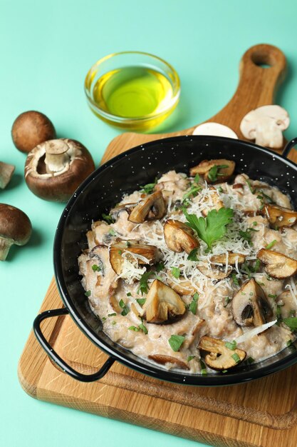 Concept of tasty food with risotto with mushrooms on mint background