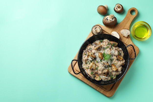 Concept of tasty food with risotto with mushrooms on mint background