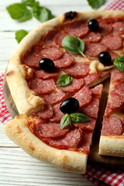 Concept of tasty food with Salami pizza on white wooden background