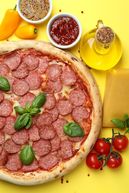 Concept of tasty food with Salami pizza on yellow background