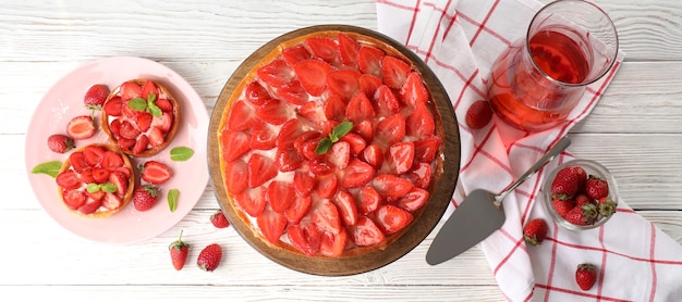 Concept of tasty food with strawberry tart on white wooden background.