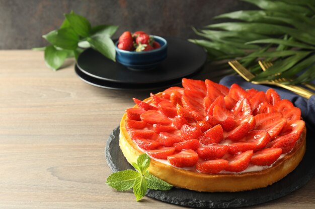 Concept of tasty food with strawberry tart on wooden table.