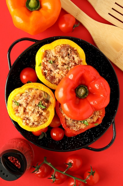 Concept of tasty food with stuffed pepper on red background