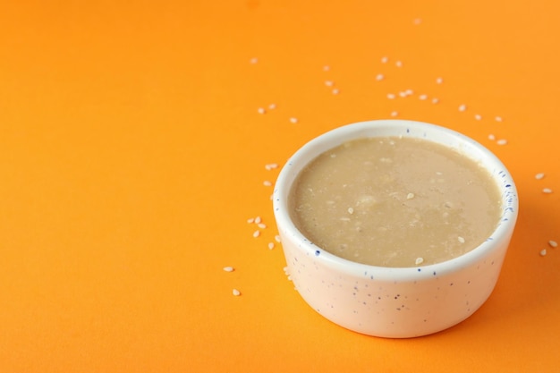 Concept of tasty food with tahini sauce on orange background