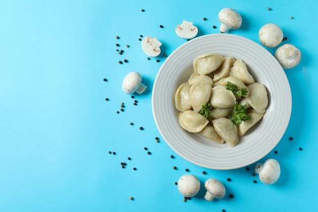 Concetto di cibo gustoso con vareniki o pierogi su superficie blu