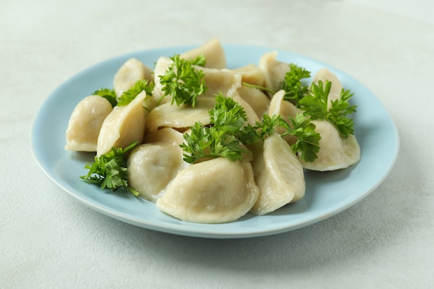 Concetto di cibo gustoso con vareniki o pierogi su tavola strutturata bianca