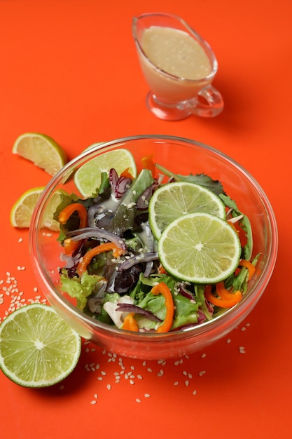 Concept of tasty food with vegetable salad with tahini sauce on orange background