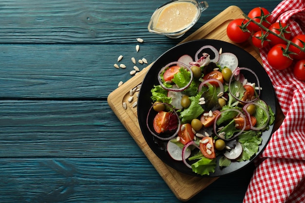 Концепция вкусной еды с овощным салатом с соусом тахини на деревянном фоне