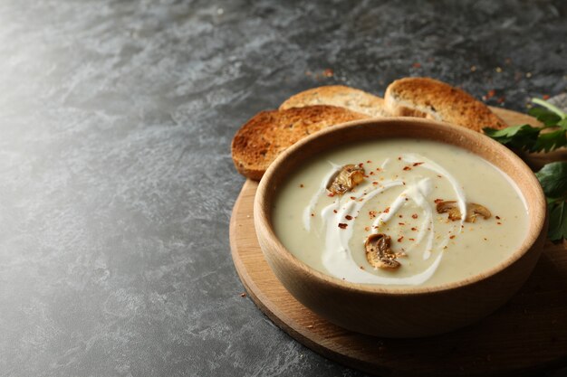 Concept of tasty lunch with bowl of mushroom soup on black smoky