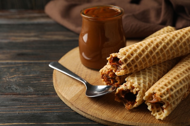 Concept of tasty meal with wafer rolls with condensed milk on wooden background