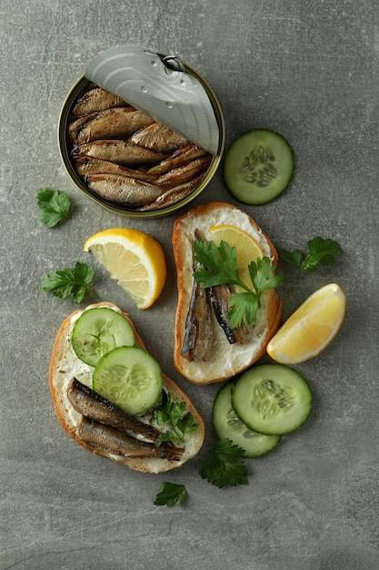 Concept of tasty snack with sandwiches with sprats on gray textured background