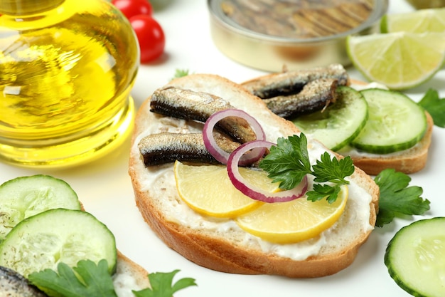 Concept of tasty snack with sandwiches with sprats on white background