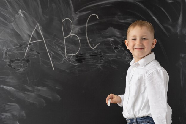 Concept terug naar school. een kleine jongen staat bij het schoolbord