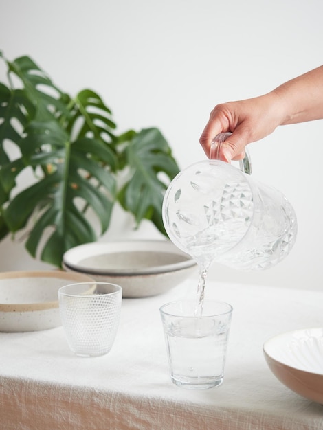 Concept of thirst and hydration Drink water healthy lifestyle Woman's hand pouring fresh and pure water from a pitcher into a glass