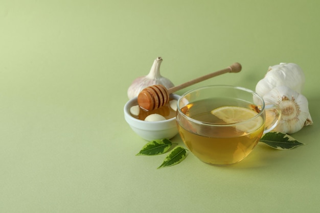 Concept of treatment colds with honey and garlic on green  background