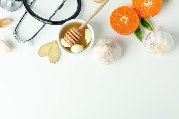 Concept of treatment colds with honey and garlic on white background