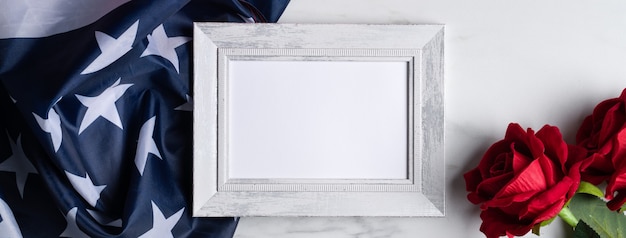 Photo concept of u.s. independence day or memorial day. national flag and red rose over bright marble table background with picture frame.