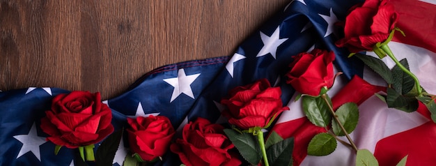 Concept of U.S. Independence day or Memorial day. National flag and red rose over dark wooden table background.