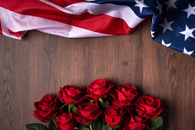 Концепция дня независимости США или Дня памяти. Национальный флаг и красная роза на фоне темного деревянного стола.