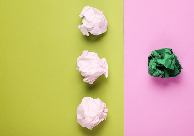 The concept of uniqueness, racial discrimination. White and green crumpled paper balls on colored background. Minimalism business