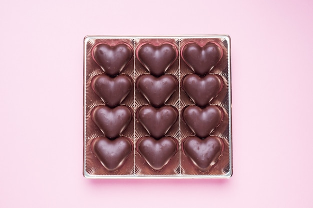 Concept Valentijnsdag. Chocoladesuikergoed, harten op een roze achtergrond