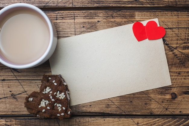 Концепция День святого Валентина. Чашка кофе и печенье на деревянном столе. Поздравительная открытка Копировать пространство