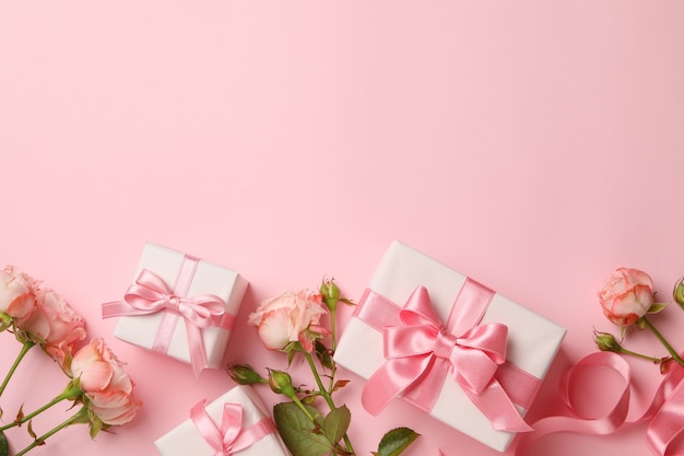 Concept of Valentine's day with gift boxes and roses on pink background