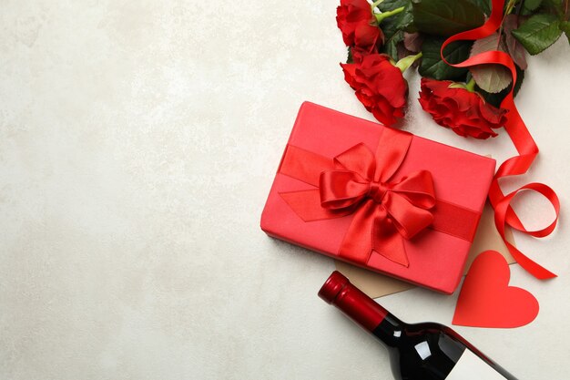白いテクスチャ背景にバラ、ワイン、ギフトボックスとバレンタインデーのコンセプト