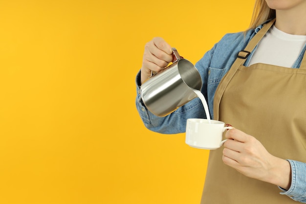 Concept van bezetting barista giet melk op gele achtergrond