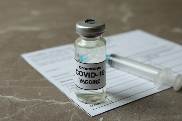 Concept van Covid - vaccinatie 19 met vaccin en spuit op grijze gestructureerde tafel