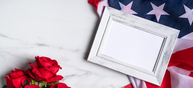 Concept van de Amerikaanse onafhankelijkheidsdag of Memorial day. Nationale vlag en rode roos over heldere marmeren tafel achtergrond met afbeeldingsframe.