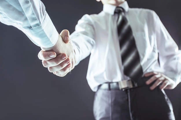 Concept van een betrouwbaar partnerschap een close-up van de handdruk van zakenpartners op een zwarte achtergrond
