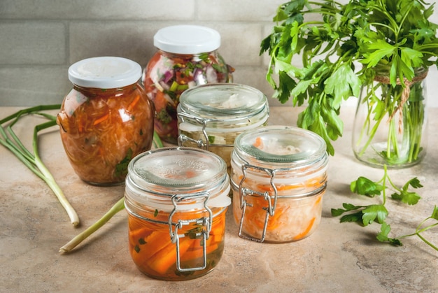 Concept van een gefermenteerde maaltijd. Thuis ingeblikt voedsel en knuppels. Veganistisch eten. Groenten. Blikken salsa in blik, zuurkool, gemarineerde wortelen, kimchi en bloemkoolbroccoli. Home keukentafel.