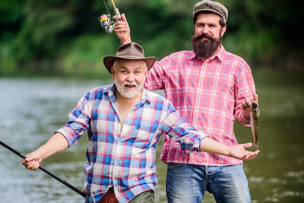 Concept van een landelijke uitje hobby Vliegvissen Tijd twee gelukkige visser met hengel en net Camping aan de oever van het meer jacht toerisme vader en zoon vissen Big game vissen vriendschap