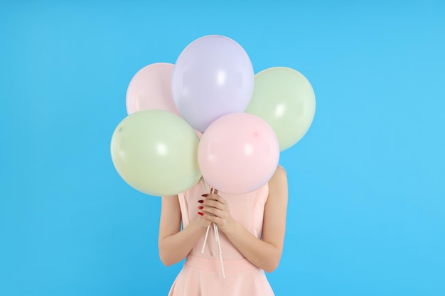 Concept van gelukkige verjaardag jonge vrouw met ballonnen op blauwe achtergrond