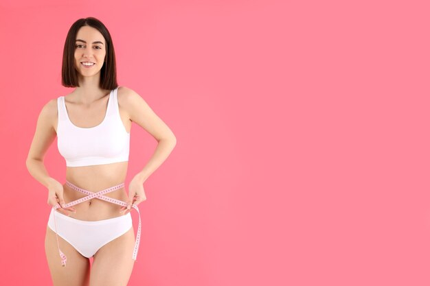 Concept van gewichtsverlies met jonge slanke vrouw op roze achtergrond