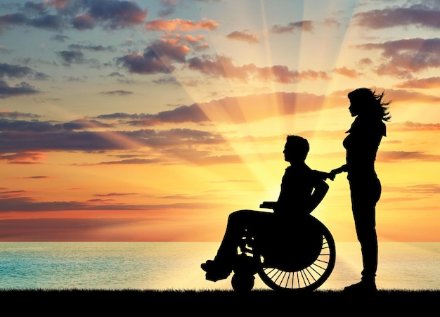 Concept van handicap en ziekte. Silhouet van gehandicapte met een voogd op de zee-zonsondergang