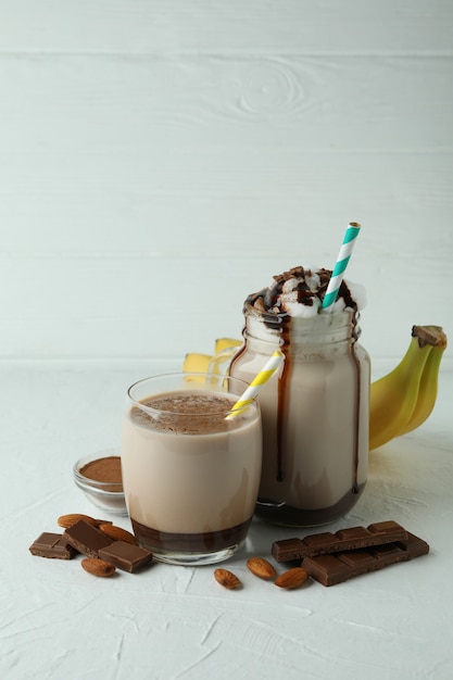 Concept van heerlijk eten met chocolade milkshake en banaan op witte getextureerde tafel