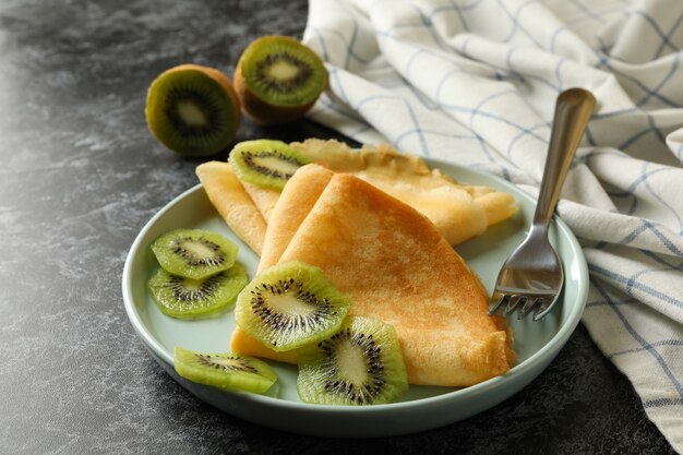Concept van heerlijk ontbijt met pannenkoeken met kiwi op zwarte smokey achtergrond