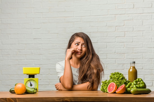 Concept van het dieet. Portret van een gezonde jonge Latijns-vrouw die bijt, nerveus en erg angstig en bang voor de toekomst, voelt paniek en stress