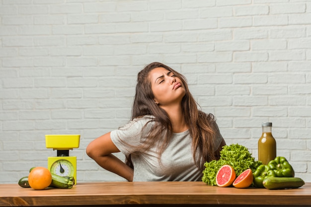 Concept van het dieet. Portret van een gezonde jonge Latijns-vrouw met pijn in de rug als gevolg van werkstress