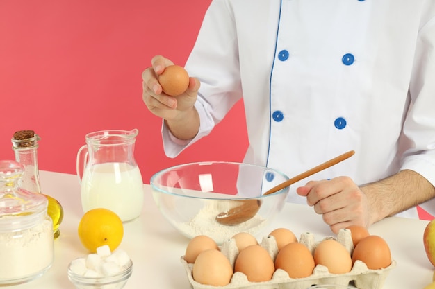 Concept van het koken van jonge chef-kok iets op roze achtergrond