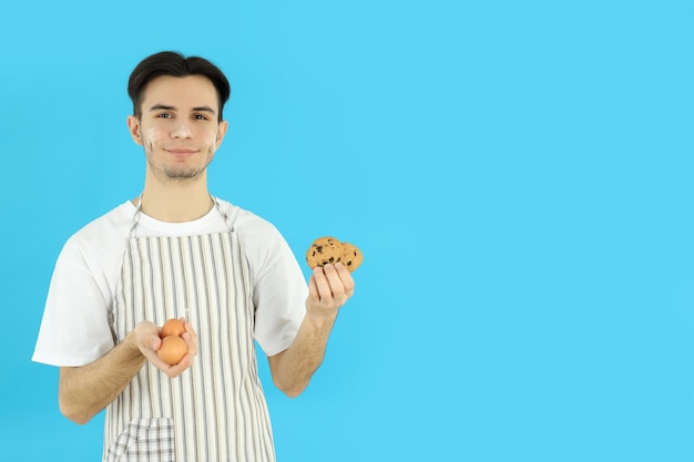 Concept van het koken van jonge man in schort op blauwe achtergrond