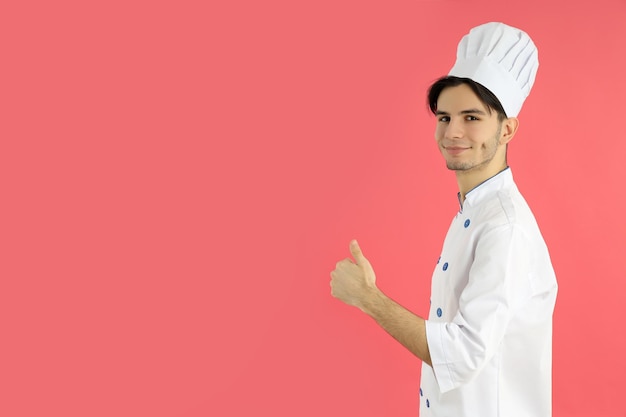 Concept van het koken van jonge mannelijke chef-kok op roze achtergrond